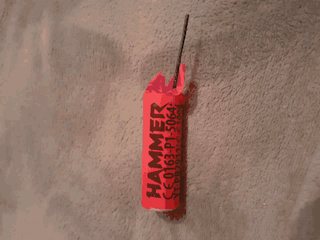 a red hammer firework sitting on a carpet