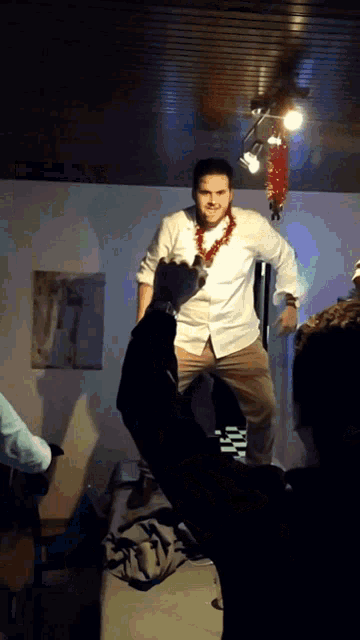 a man in a white shirt is dancing in a room with other people