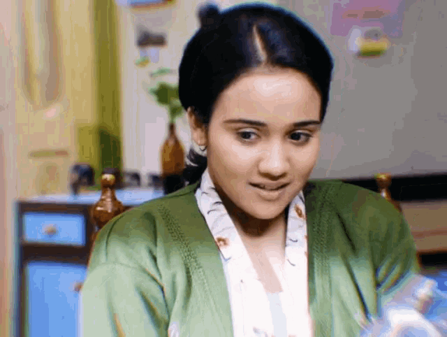 a woman wearing a green cardigan is looking at something