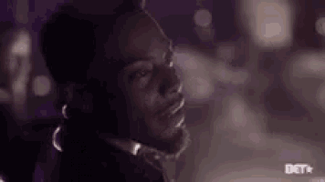 a man with a beard is wearing headphones and looking at the camera in a dark room .