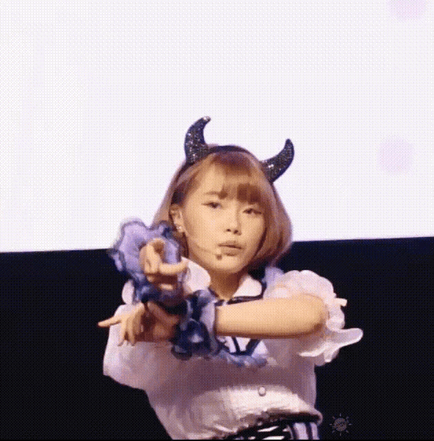 a girl with horns on her head is pointing her finger