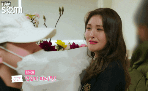 a woman is crying while holding a bag of flowers in front of her
