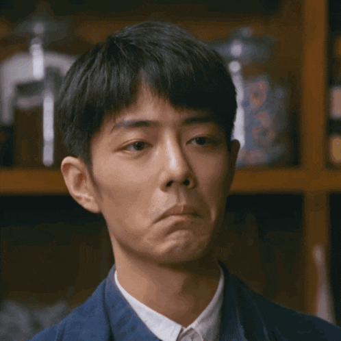a man in a blue jacket and white shirt is making a sad face