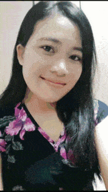 a woman with long black hair is smiling and wearing a floral top
