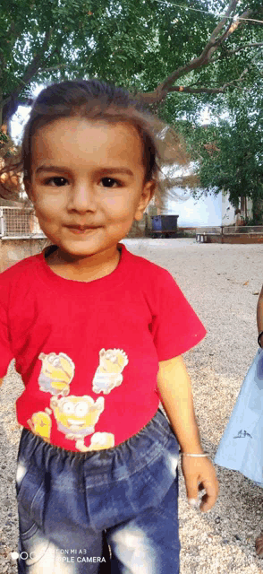 a little girl wearing a red shirt with a picture of simpson characters on it