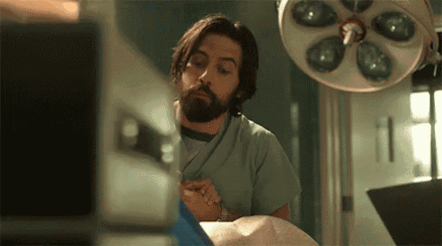 a man with a beard is standing in an operating room with a patient .