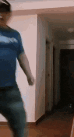 a man in a blue shirt is dancing in a hallway .