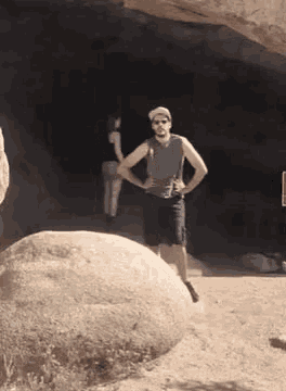 a man is standing on a large rock in the desert .