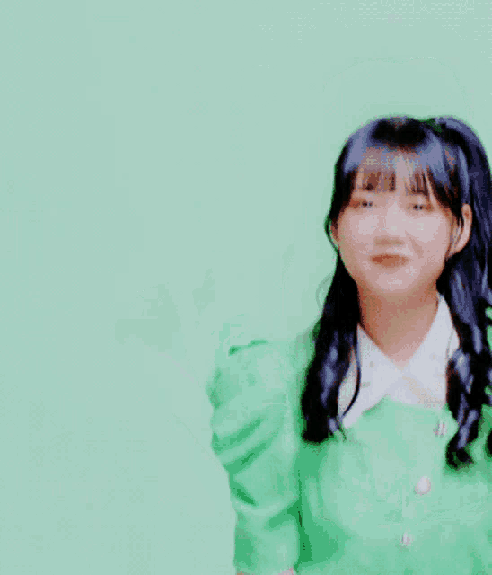 a girl in a green shirt is smiling and giving the peace sign