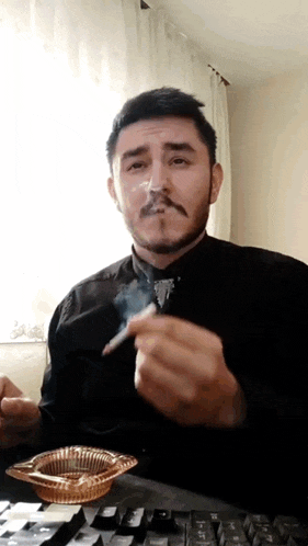 a man is smoking a cigarette in front of a keyboard