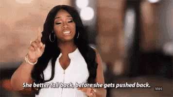a woman is giving a thumbs up sign and saying `` she better fall back before she gets pushed back '' .