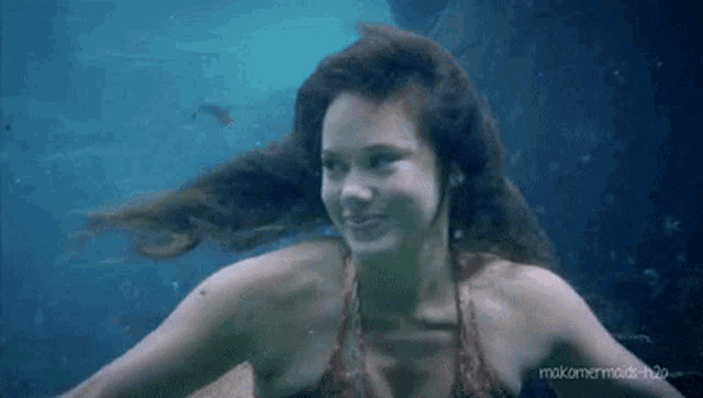 a woman is swimming underwater in a bikini and smiling .
