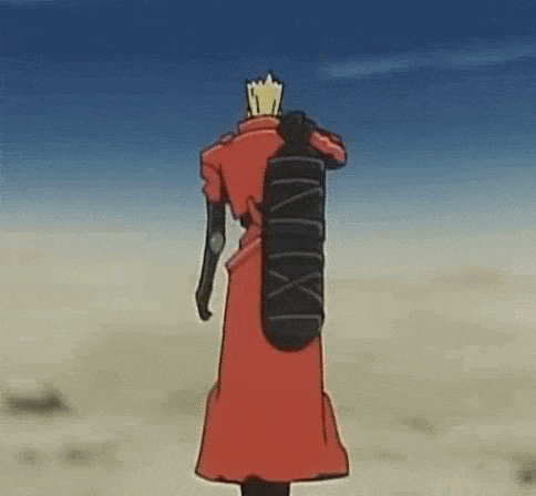 a man in a red coat is standing in the desert holding a skateboard on his back .