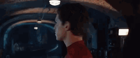 a close up of a man in a red spiderman suit standing in a dark room .