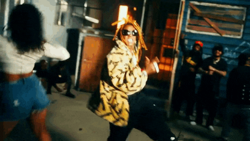a man with dreadlocks is dancing in front of a group of people