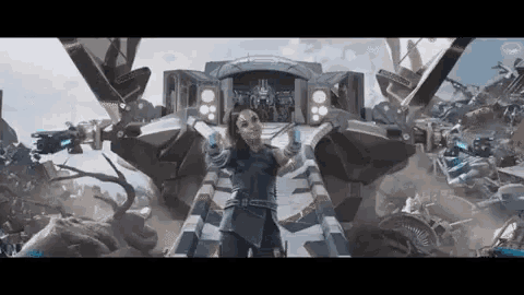 a woman is standing in front of a large robot in a movie .