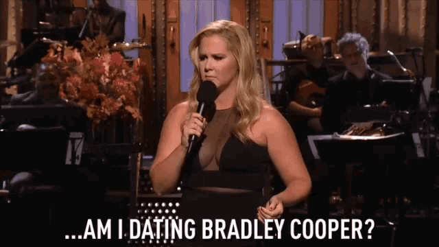 a woman in a black dress is holding a microphone and asking am i dating bradley cooper