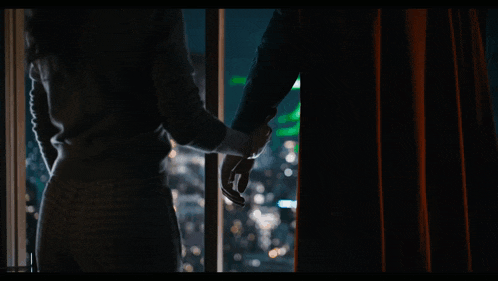 a man and a woman holding hands looking out a window