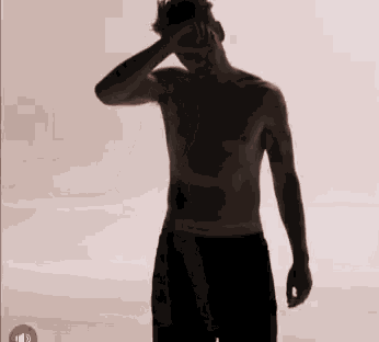 a shirtless man is standing in a silhouette with his hand on his head .
