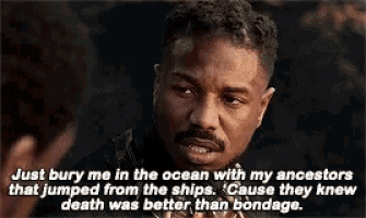 a man with a beard is talking to another man in a movie scene .