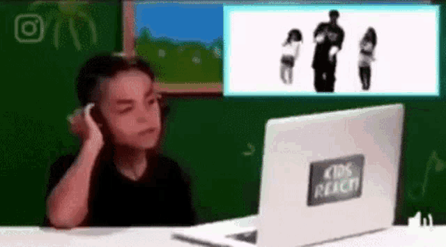 a young boy is sitting in front of a laptop computer with a kids react sticker on it .
