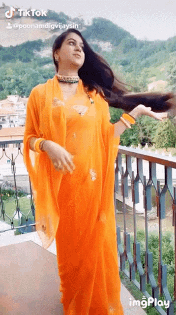a woman in an orange dress stands on a balcony