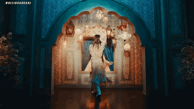 a woman in a white robe is standing in a room with a blue wall and a sign that says whereinarcade