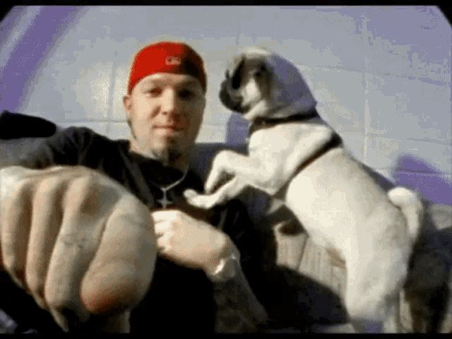a man in a red hat is holding a small dog