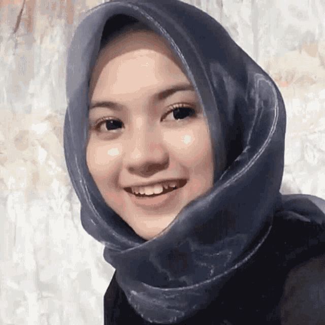 a woman wearing a blue scarf around her head smiles for the camera
