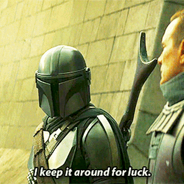 a man in a helmet is talking to another man and says " i keep it around for luck "