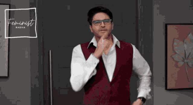 a man wearing glasses and a vest stands in front of a sign that says feminist