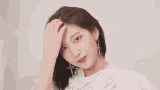 a close up of a girl wearing a white dress and earrings .