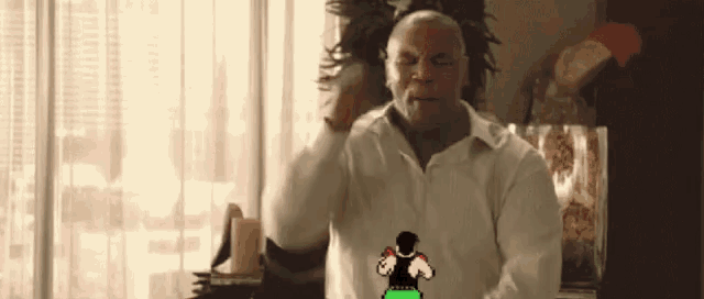 a man in a white shirt is standing in front of a window with a cartoon of a man boxing behind him .