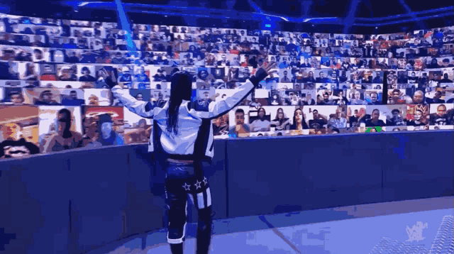 a wrestler is standing in front of a crowd with their arms outstretched