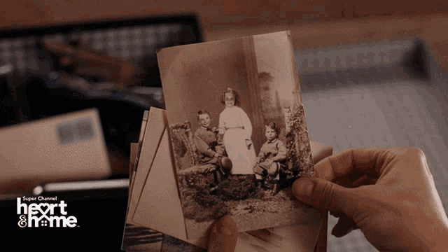 a person is holding a picture of a family in front of a sign that says " heart & home "
