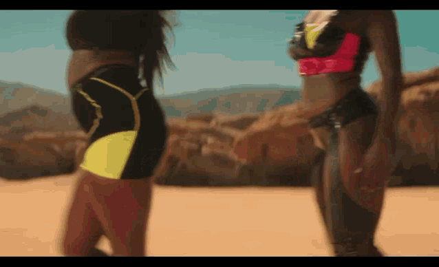 two women in bikinis are standing next to each other on a beach