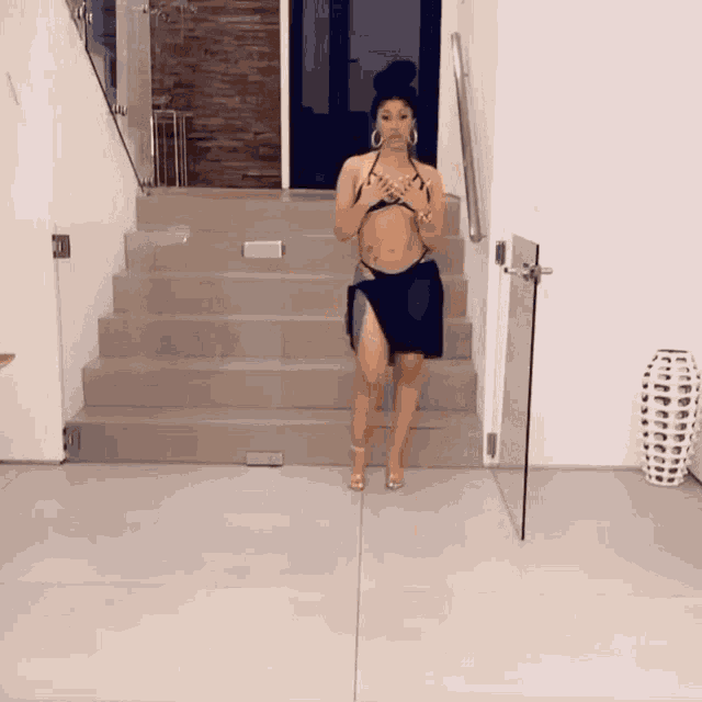 a woman in a bikini is walking down a set of stairs in a room .