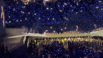 a crowd of people are watching a concert with a lot of lights on the stage