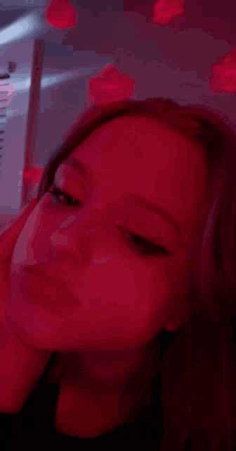 a woman 's face is shown in a blurry photo with red lights in the background