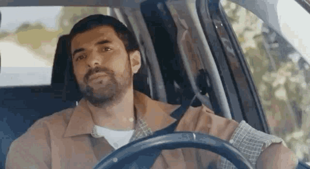 a man is sitting in the driver 's seat of a car .