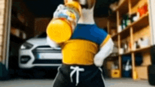 a dog in a yellow and blue shirt is holding a bottle of orange juice in a garage .