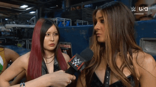 two women talking in front of a sign that says ' champions ' on it