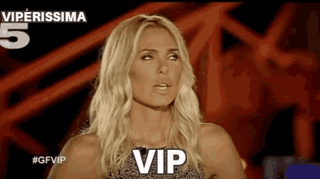 a woman with blonde hair is standing in front of a red background and says vip .