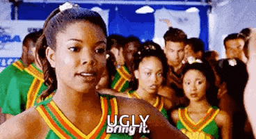 a group of cheerleaders are standing in a line and one of them is wearing a green and yellow uniform .