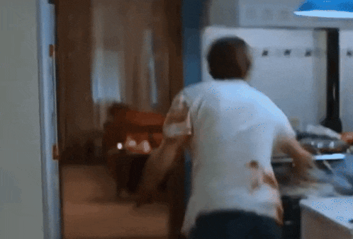 a man in a white shirt is standing in the kitchen
