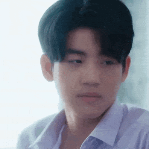 a close up of a young man wearing a white shirt and looking at the camera .