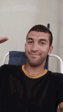 a man with a beard is sitting in a chair and smiling
