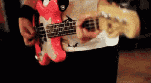 a man is playing a red bass guitar in a room .