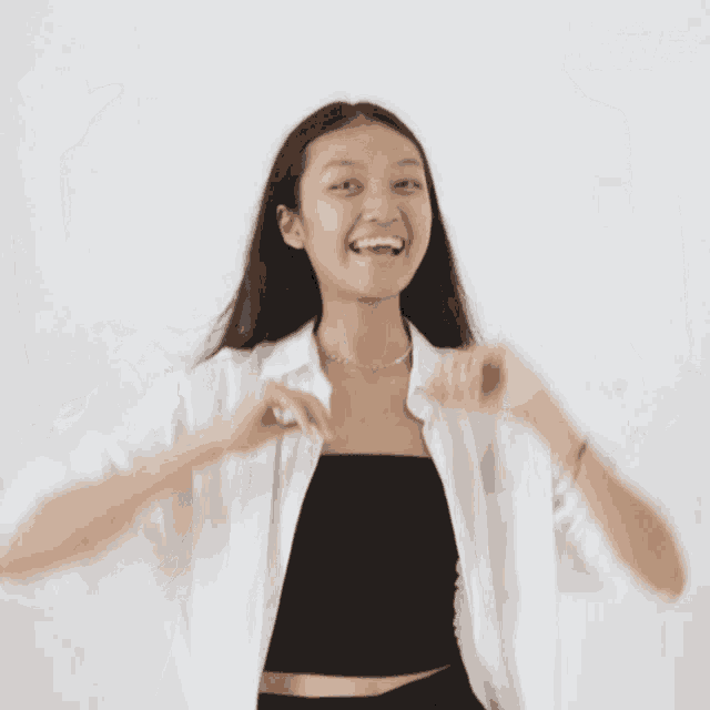 a woman wearing a white shirt and a black tank top has her arms in the air and says jfw on the bottom right