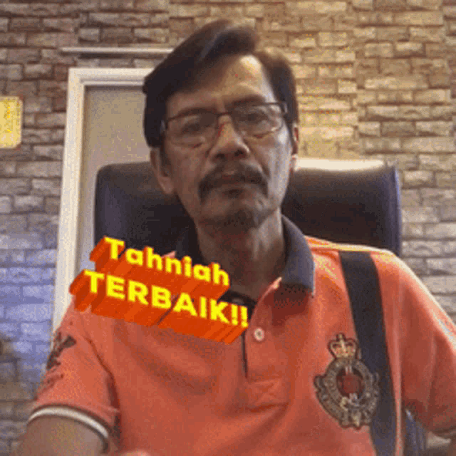 a man wearing glasses and an orange shirt has a sticker that says tahniah terbaik